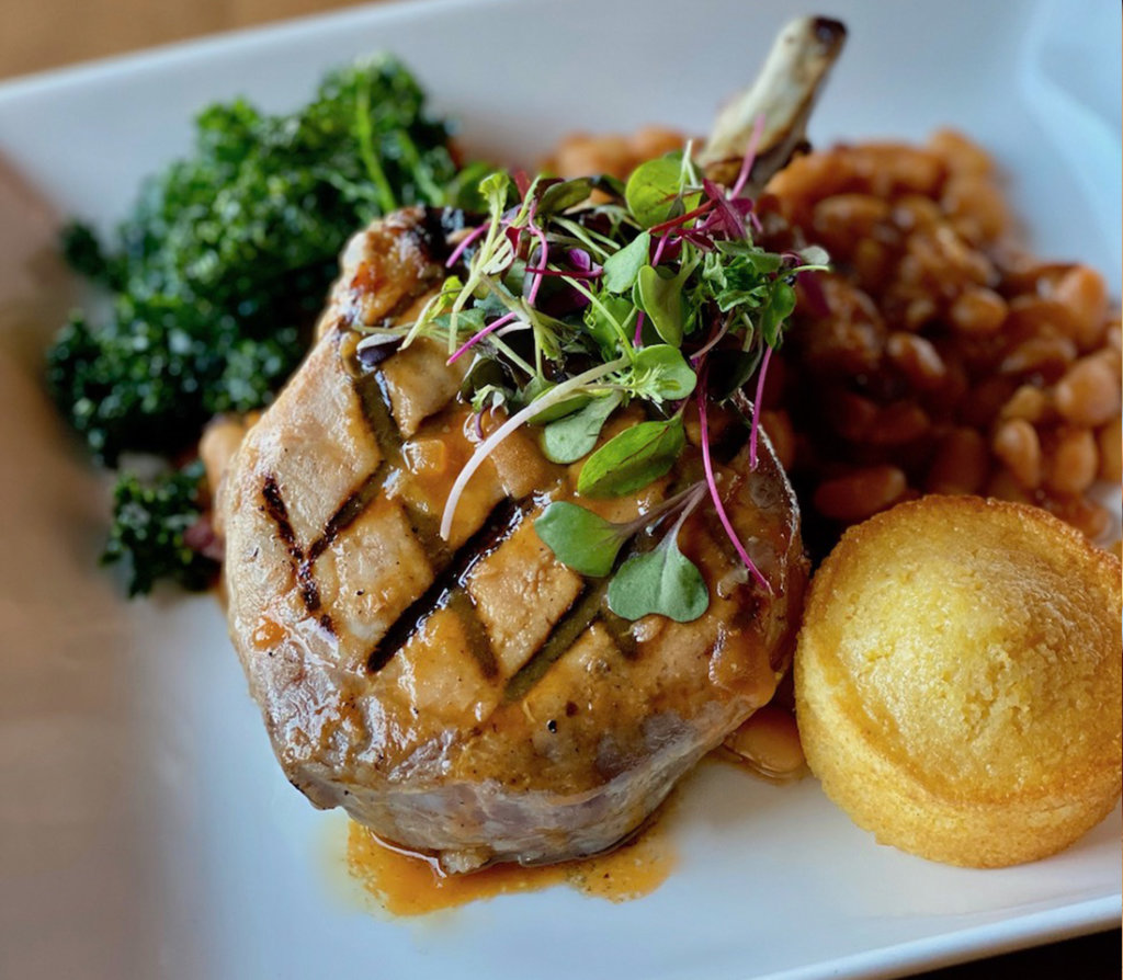 Tomahawk Pork Chop with Bacon n' Beans at The Cache at Ginger and Baker