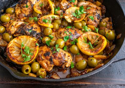 Chicken thighs, olives, and lemons cooked in a cast iron skillet