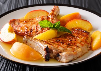 Organic food: grilled spicy pork with glazed fresh peaches and mint closeup on a plate. horizontal