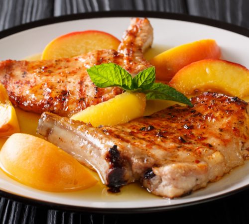 Organic food: grilled spicy pork with glazed fresh peaches and mint closeup on a plate. horizontal