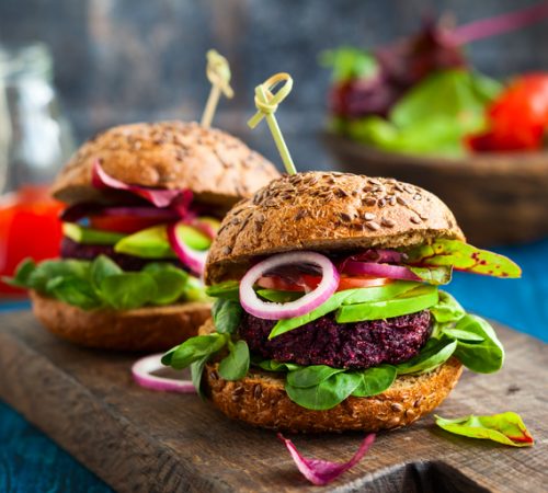 Veggie beet and quinoa burger with avocado on the vintage wooden board